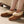 Acorn brown suede slippers with cream faux fur lining worn on feet