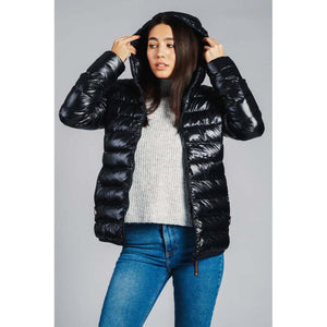Woman wearing a black 8K FlexWarm hooded puffer jacket over a grey sweater and blue jeans