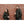 Man and woman wearing black ActionHeat hooded jackets standing against a brick wall holding coffee cups