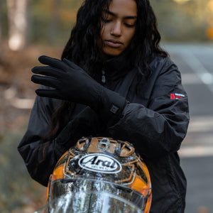 Person wearing black Venture Heat heated gloves and holding an Arai helmet